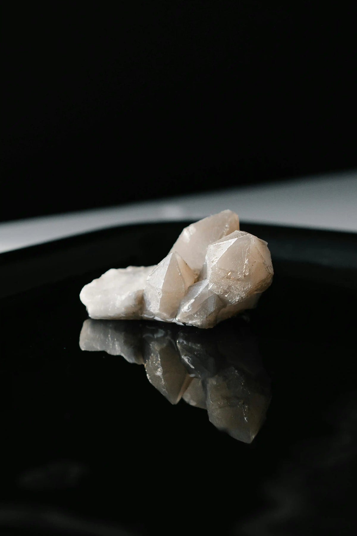 Natural quartz crystal on a reflective black surface